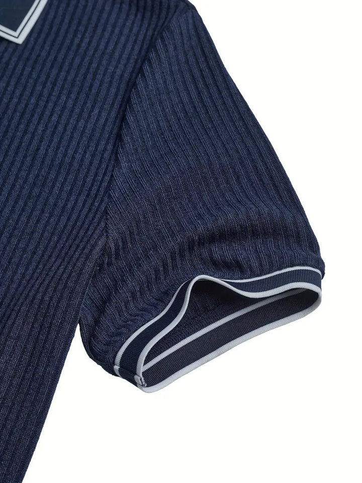 Dunkelblaues Herren-Poloshirt aus geripptem Stoff mit kontrastierenden Streifen an den Ärmelbündchen.