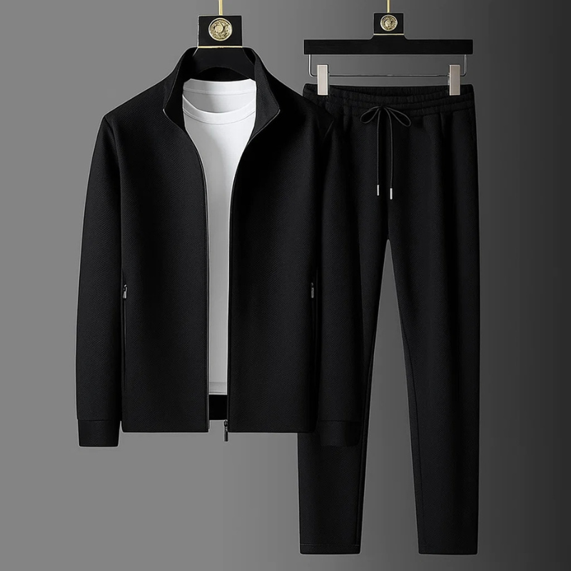 Schwarzer Herren-Zweiteiler mit Stehkragen, Reißverschlussjacke und Hose mit Kordelzug in strukturierter Optik.