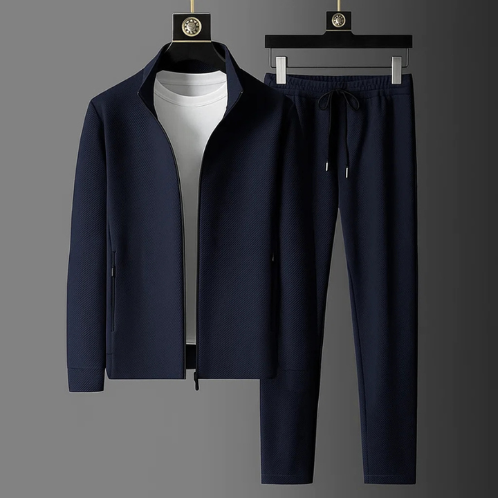 Dunkelblauer Herren-Zweiteiler mit strukturierter Jacke, Stehkragen, Reißverschluss und passender Hose mit Kordelzug.