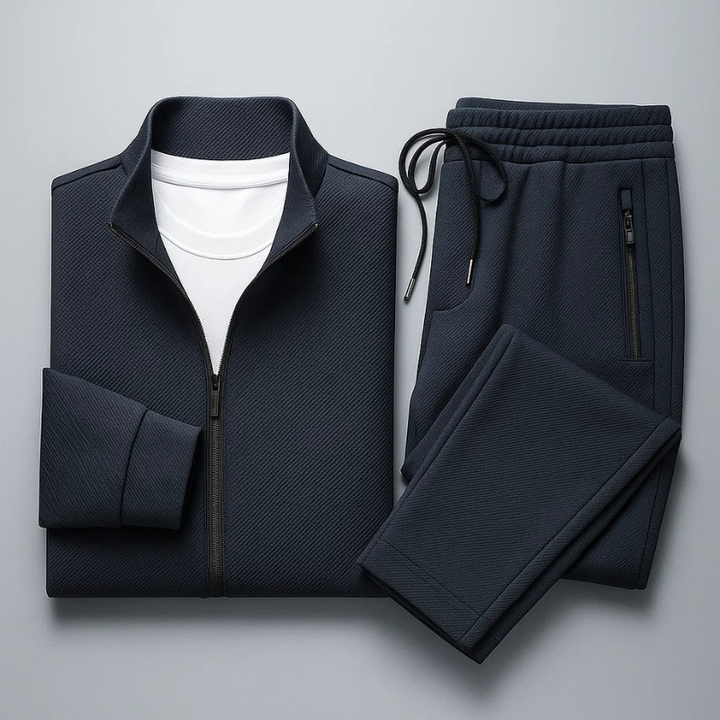Dunkelblauer Herren-Zweiteiler mit Reißverschluss-Jacke, Stehkragen und Hose mit Kordelzug in feiner Struktur-Optik.