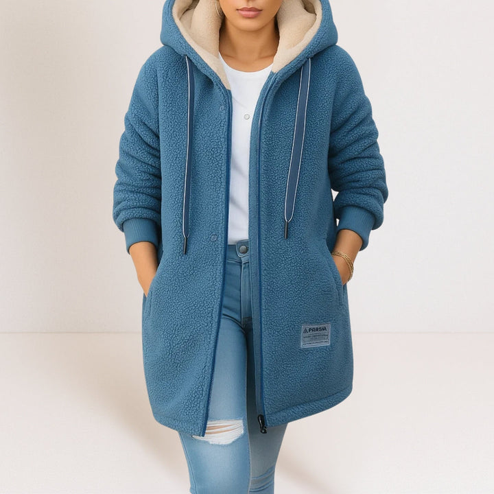 Blaue Longline-Sherpa-Kapuzenjacke für Damen mit beigem Innenfutter, Reißverschluss und praktischen Seitentaschen.