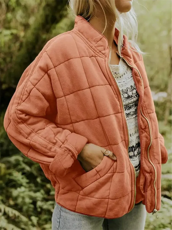 Locker geschnittene, korallenrote Steppjacke mit Karomuster, Stehkragen und praktischem Reißverschluss für die Übergangszeit.