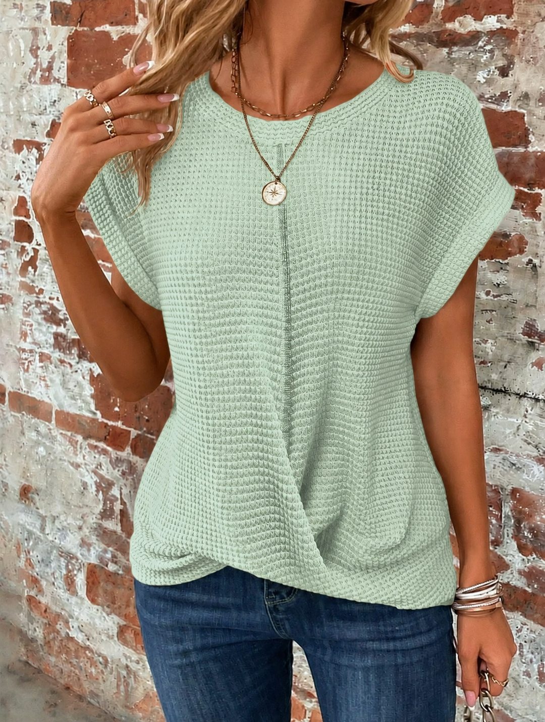 Hellgrünes Damen-Shirt aus Waffelstrick mit Rundhalsausschnitt, gerollten Ärmeln und modischem Front-Twist am Saum.