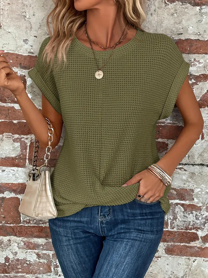 Olivgrünes Damen-Shirt aus Waffelstrick mit Rundhals, gerollten Kurzärmeln und modischem Front-Twist am Saum.