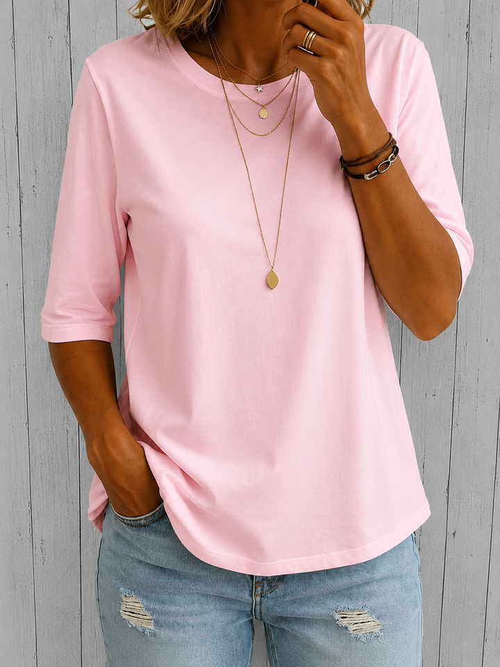 Hellrosa Damen-Shirt mit Rundhals und Halbarm-Ärmeln in lockerer Passform, kombiniert mit einer hellblauen Jeans.