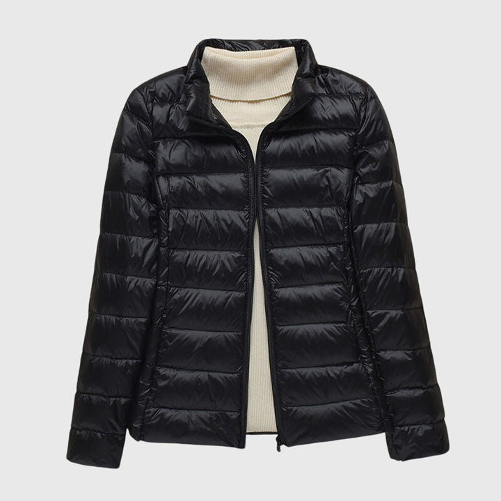 Schwarze, leicht gesteppte Damenjacke mit Reißverschluss über einem cremeweißen Rollkragenpullover.