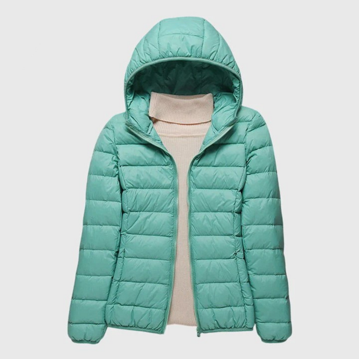 Hellgrüne, leichte Damen-Steppjacke Anouk mit Kapuze und Reißverschluss über einem beigen Rollkragenpullover.