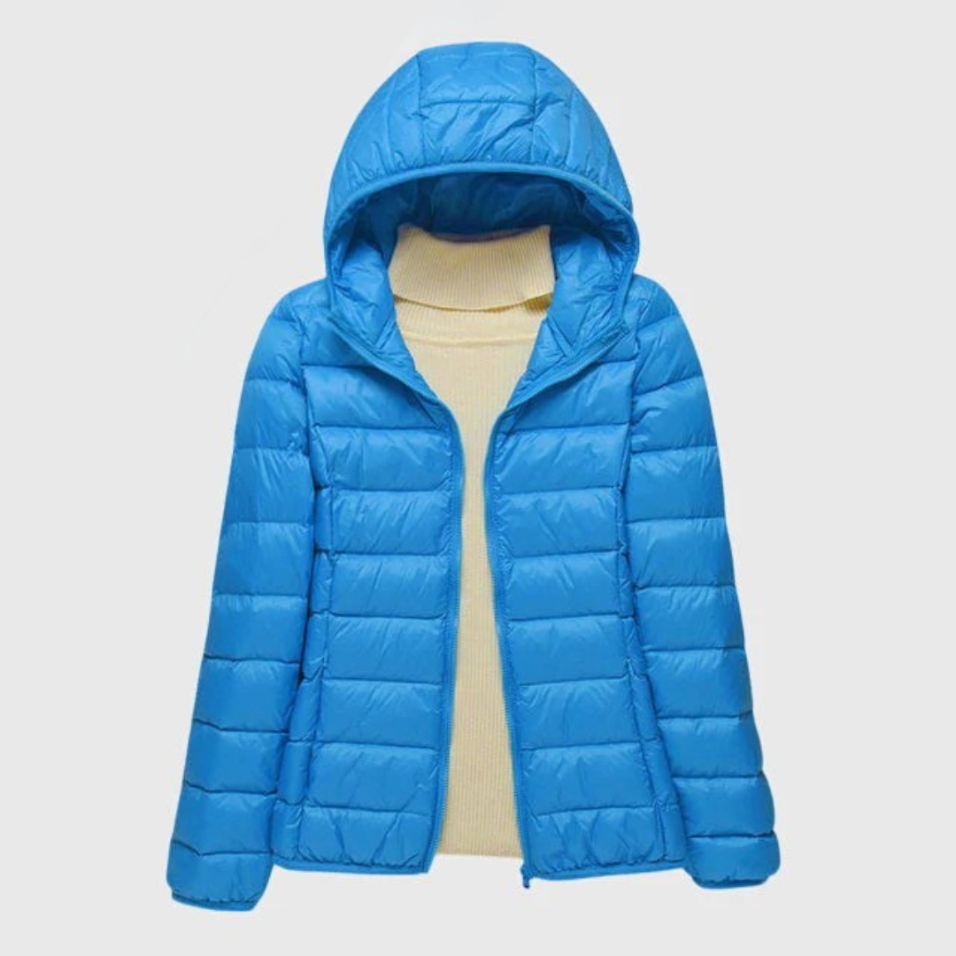 Leuchtend blaue, leicht gesteppte Damenjacke mit Kapuze und Reißverschluss über einem beigen Rollkragenpullover.