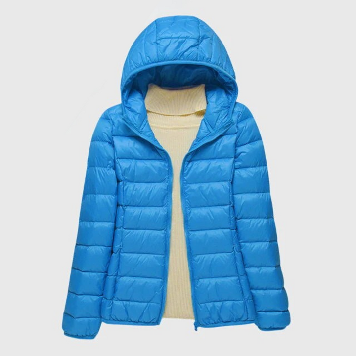 Leuchtend blaue, leicht gesteppte Damenjacke mit Kapuze und Reißverschluss über einem beigen Rollkragenpullover.