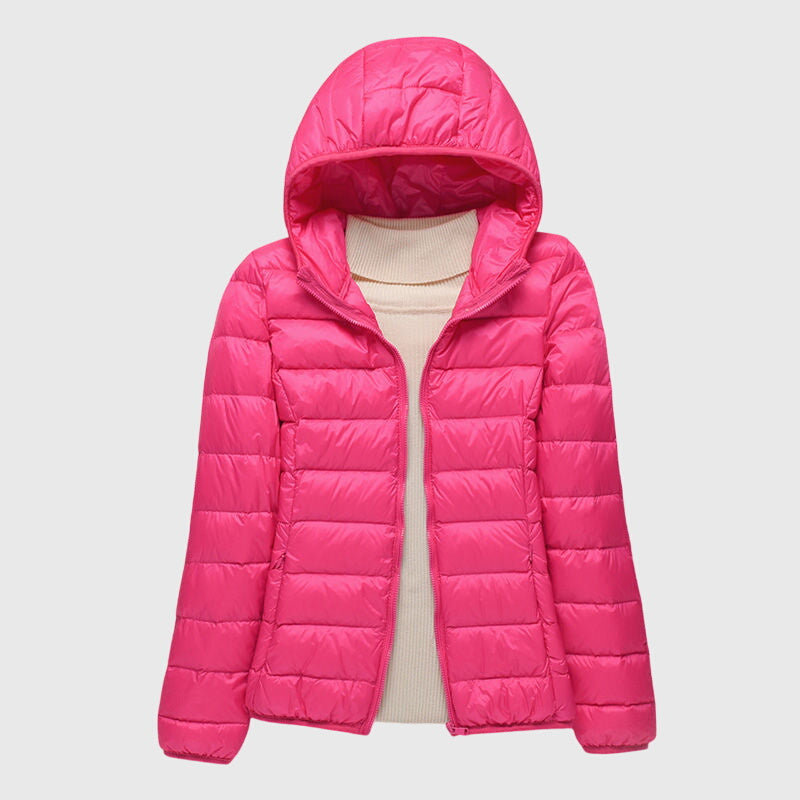 Pinke, leicht gesteppte Damenjacke Anouk mit Kapuze und durchgehendem Reißverschluss über einem beigen Pullover.