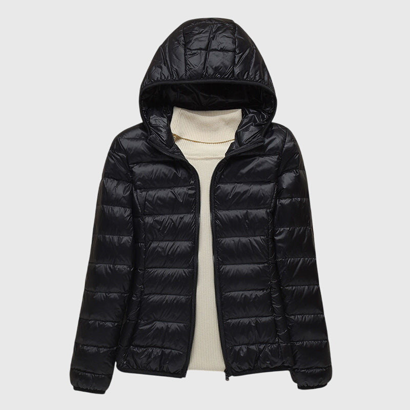 Schwarze, leicht gesteppte Damenjacke Anouk mit Kapuze und durchgehendem Reißverschluss über einem beigen Rollkragenpullover.