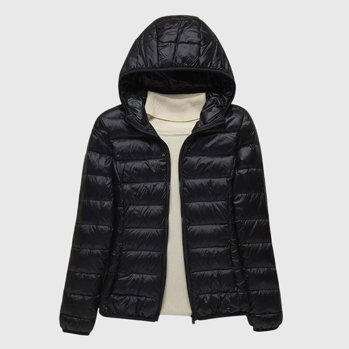 Schwarze, leicht gesteppte Damenjacke Anouk mit Kapuze und durchgehendem Reißverschluss über einem beigen Rollkragenpullover.
