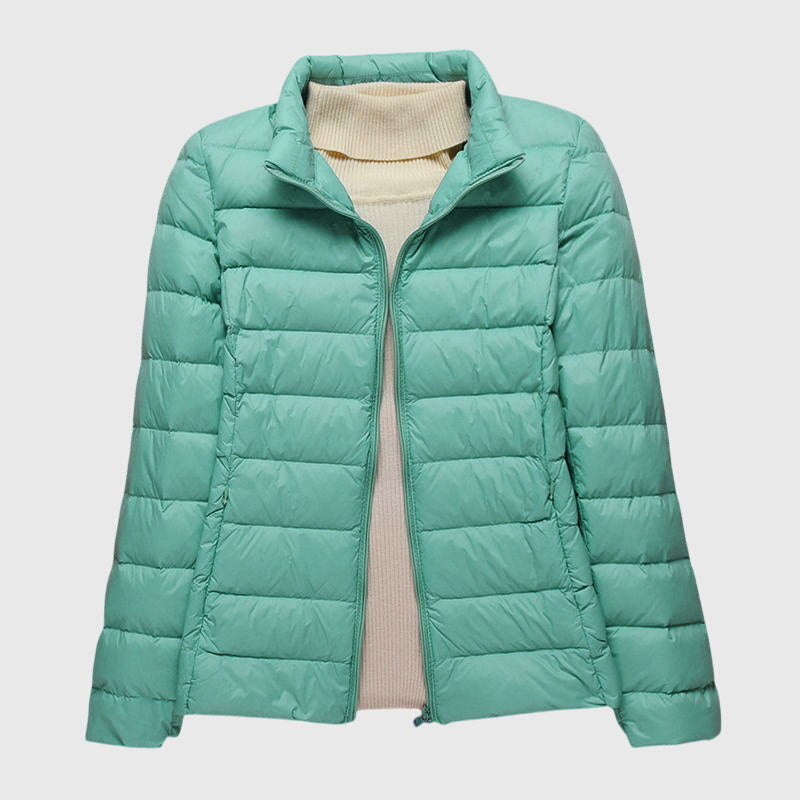 Hellgrüne, leichte Damen-Steppjacke mit Reißverschluss über einem beigen Rollkragenpullover.