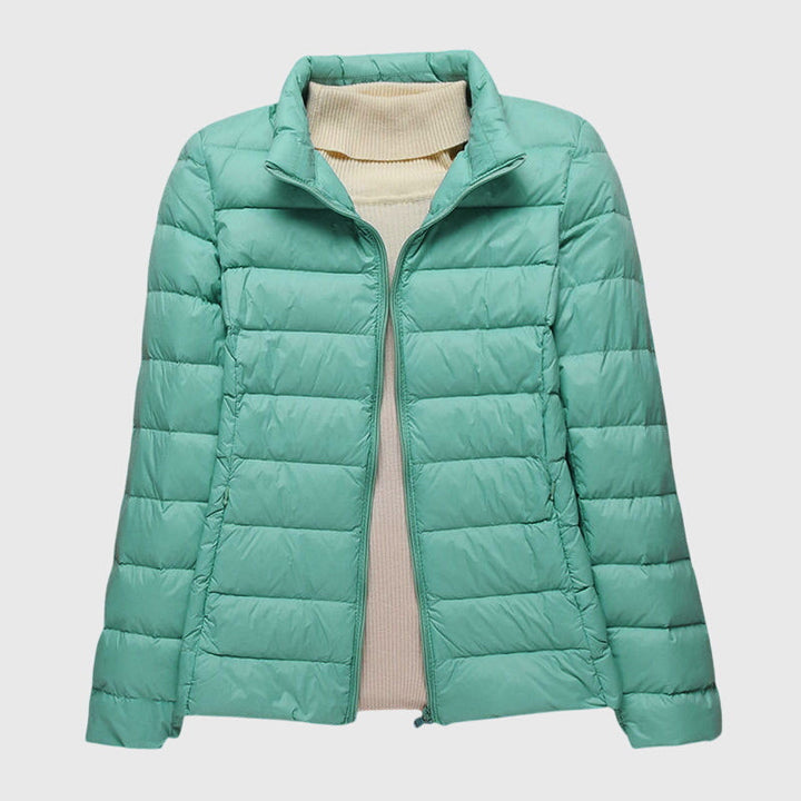 Hellgrüne, leichte Damen-Steppjacke mit Reißverschluss über einem beigen Rollkragenpullover.