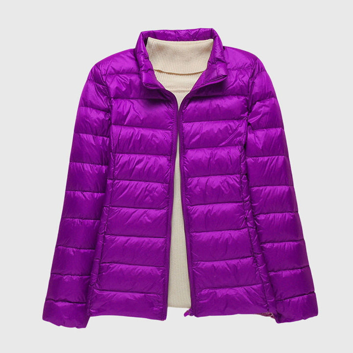 Violette, leicht gesteppte Damen-Übergangsjacke mit Reißverschluss und beigem Rollkragenpullover darunter.