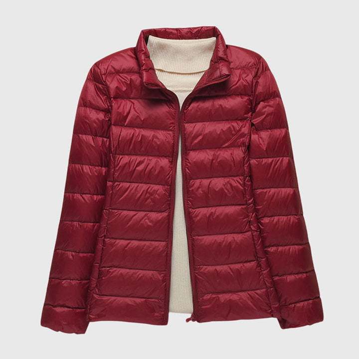 Dunkelrote, leicht gesteppte Damen-Übergangsjacke mit Reißverschluss über einem beigen Rollkragenpullover.