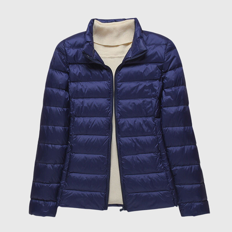Dunkelblaue, leicht gesteppte Damenjacke mit Reißverschluss und hellem Rollkragenpullover darunter.