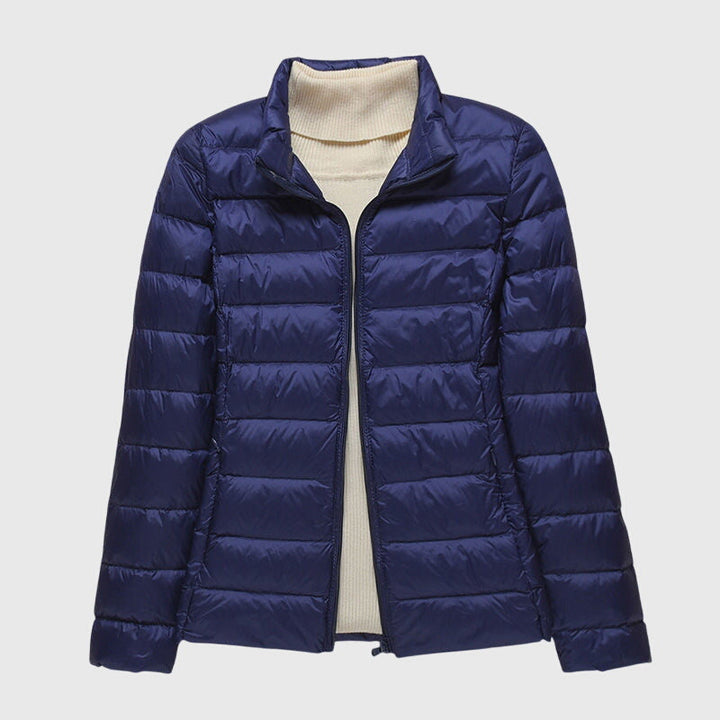 Dunkelblaue, leicht gesteppte Damenjacke mit Reißverschluss und hellem Rollkragenpullover darunter.