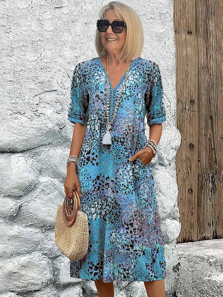 Blaues Midikleid mit V-Ausschnitt, Blumenmuster, kurzen Ärmeln und praktischen Seitentaschen für den Sommer.