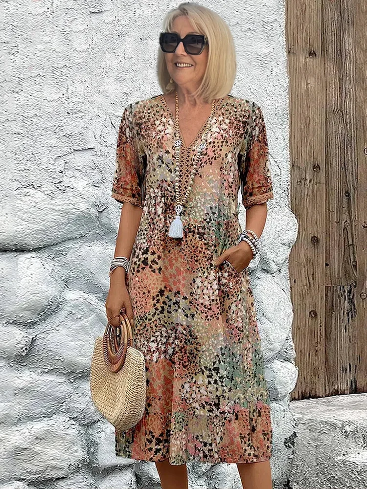 Frau trägt ein buntes Midikleid mit V-Ausschnitt, Blumenmuster, kurzen Ärmeln und praktischen Seitentaschen.