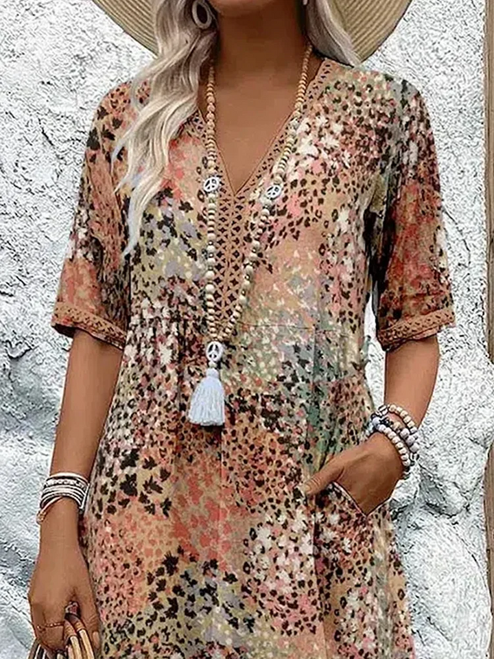 Buntes Midikleid mit V-Ausschnitt, Blumenmuster, kurzen Ärmeln und praktischen Seitentaschen im sommerlichen Stil.