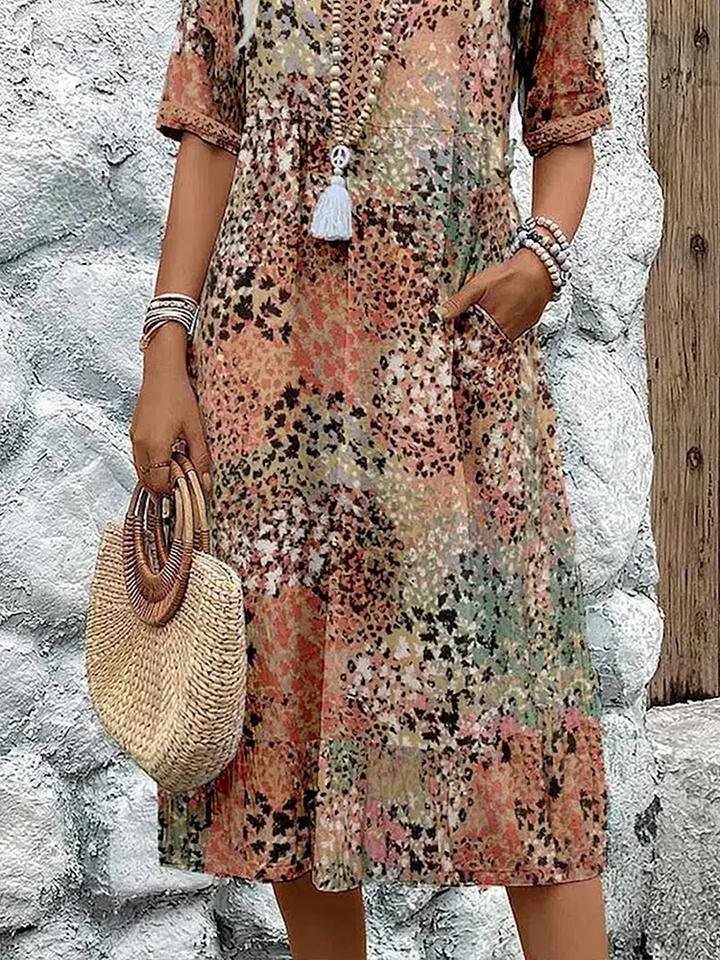 Buntes Midikleid mit Blumenmuster, V-Ausschnitt, kurzen Ärmeln und praktischen Seitentaschen im sommerlichen Stil.