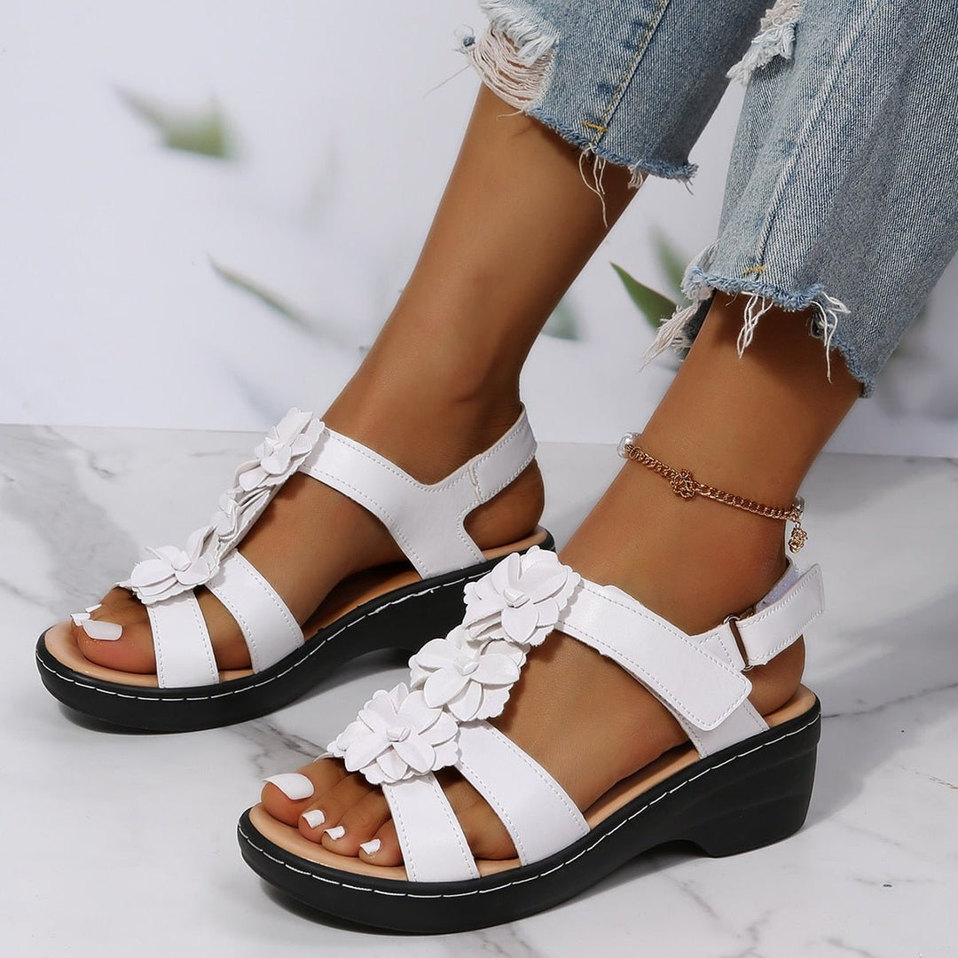 Weiße Clara Keilsandalen für Damen mit dekorativen Blütenakzenten und schwarzer Sohle.