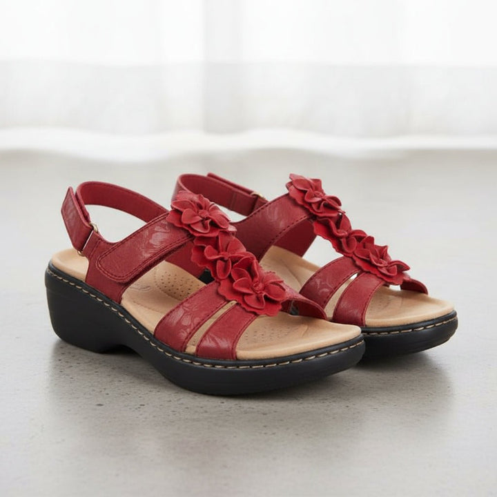 Rote Clara Damen-Keilsandalen aus Leder mit dekorativen Blüten und schwarzer Sohle.