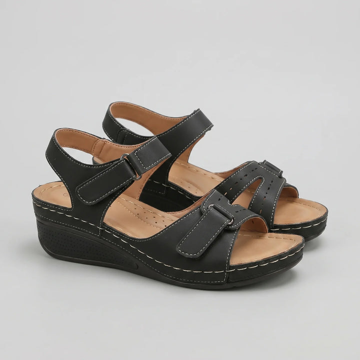 Schwarze Clara Damen Keilsandalen mit verstellbaren Riemen, offener Zehenpartie und bequemer niedriger Keilsohle.