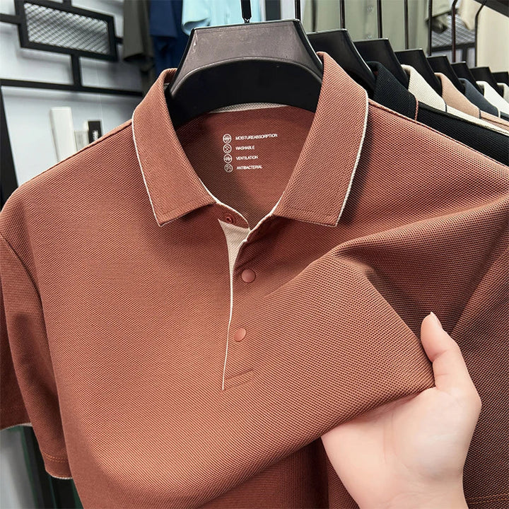 Braunes Herren-Poloshirt aus strukturiertem Piqué-Stoff mit klassischem Kragen und Knopfleiste auf einem Kleiderbügel.