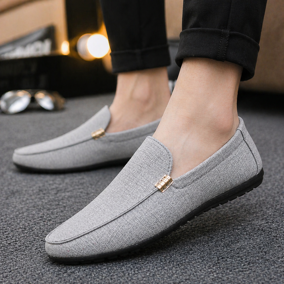 Grauer Herren-Slip-On-Loafer aus strukturiertem Canvas mit schlichter Silhouette und dezenter Metallapplikation.