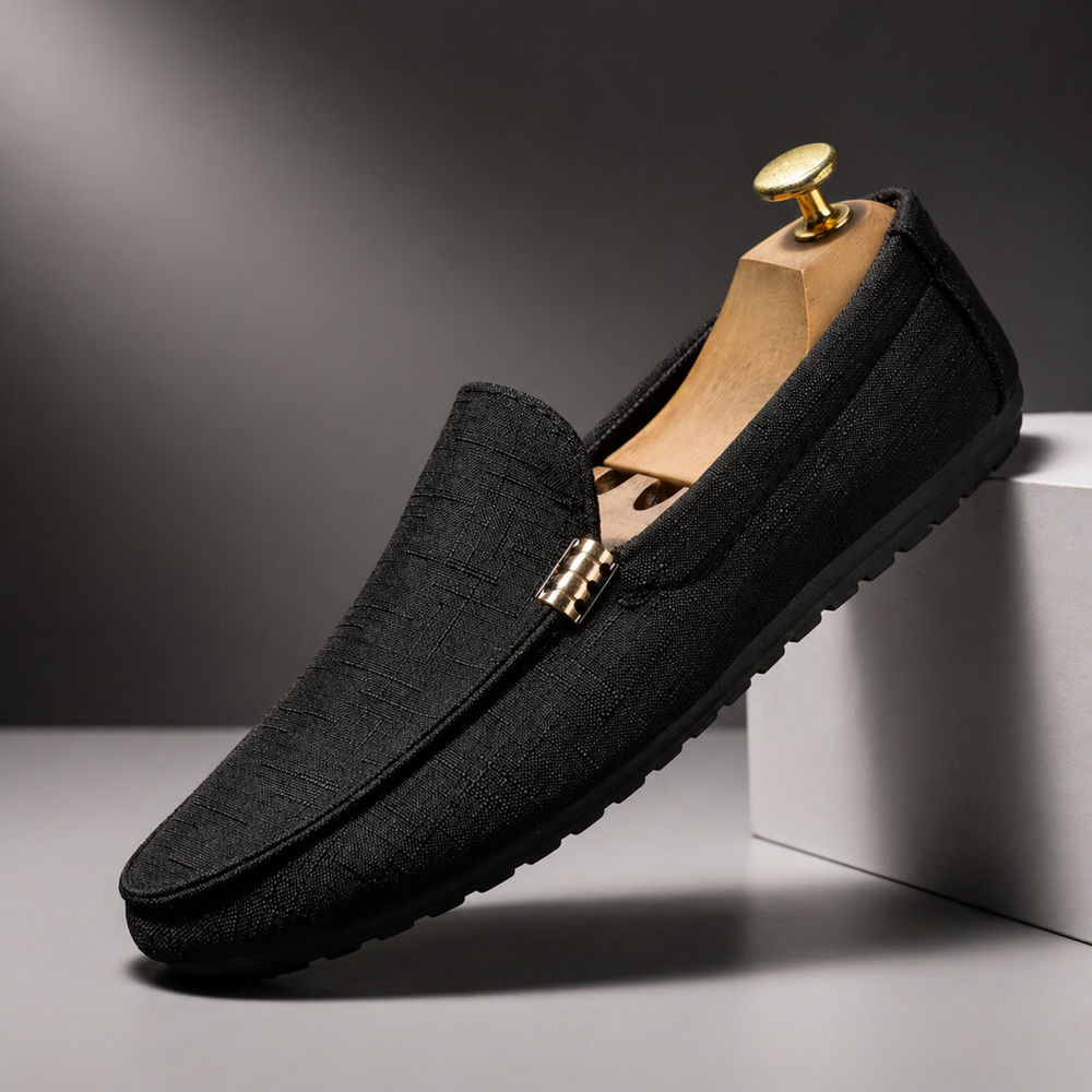 Schwarzer Herren-Loafer aus strukturiertem Canvas mit Slip-On-Design und dekorativem Metallelement auf einem Schuhspanner.