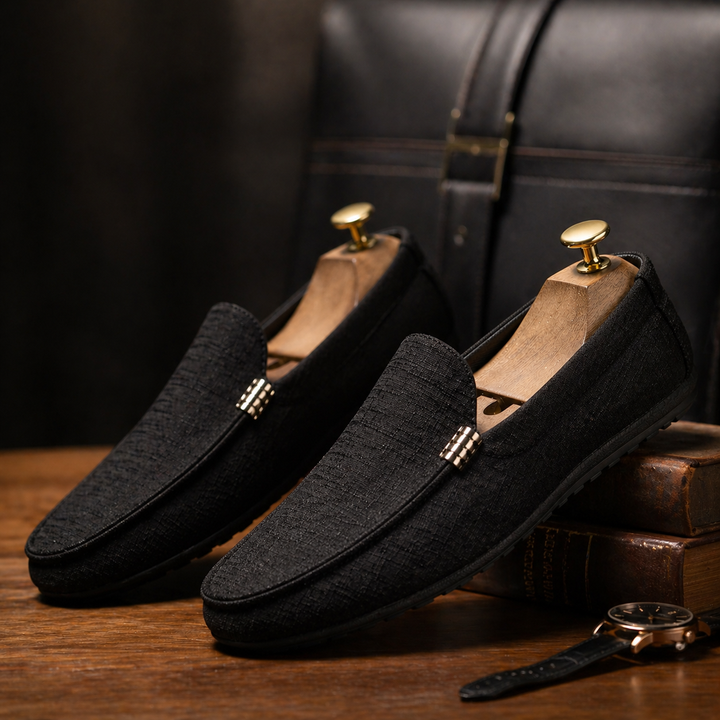 Schwarzer Herren-Loafer aus strukturiertem Canvas im Slip-On-Design mit flexibler Sohle auf einem Holztisch.
