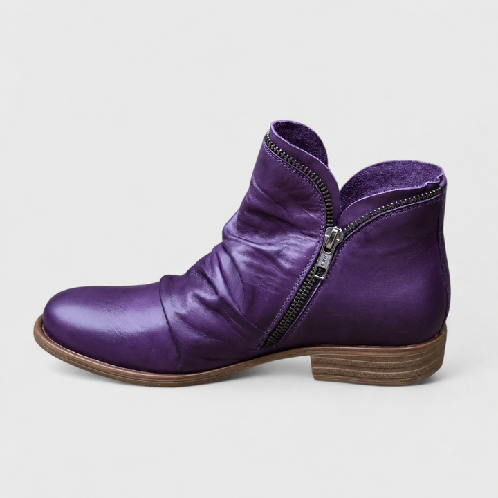 Violette Damen-Stiefeletten in Lederoptik mit gerafftem Schaft, seitlichem Reißverschluss und niedrigem Blockabsatz.
