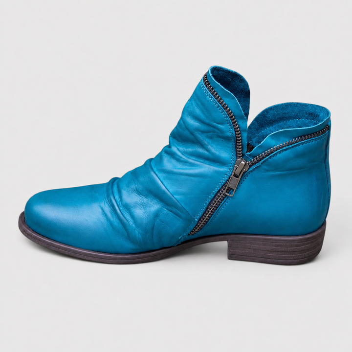 Blaue Damen-Stiefeletten in Lederoptik mit gerafftem Obermaterial, seitlichem Reißverschluss und niedrigem Blockabsatz.