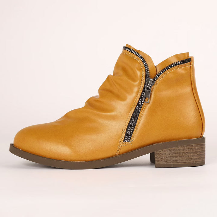 Senfgelbe Damen-Stiefeletten mit gerafftem Obermaterial, seitlichem Reißverschluss und niedrigem Blockabsatz.