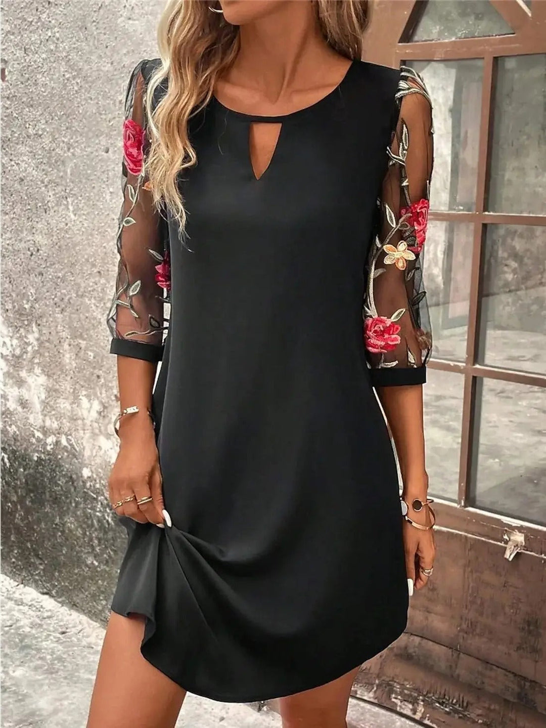 Schwarzes Minikleid mit Rundhals-Cut-Out und transparenten 3/4-Mesh-Ärmeln mit floraler Stickerei.