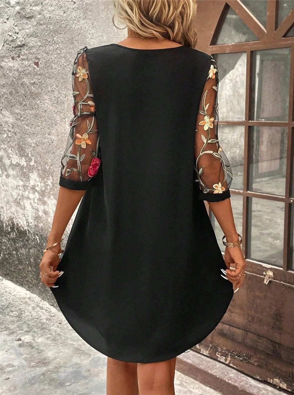 Schwarzes Minikleid mit transparenten 3/4-Mesh-Ärmeln und bunter floraler Stickerei in fließender Passform.