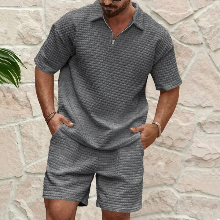 Graues Herren-Set aus Waffelstoff mit Poloshirt, kurzem Reißverschluss und passenden Shorts im lockeren Schnitt.