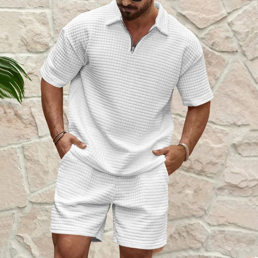 Weißes Herren-Sommerset aus Waffelstoff mit Poloshirt, kurzem Reißverschluss und passenden Shorts.