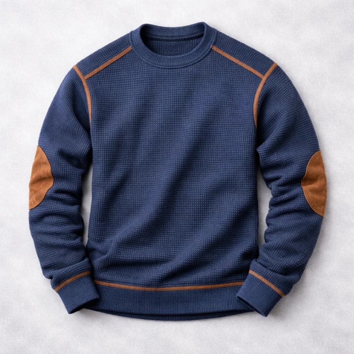Dunkelblauer Herren-Waffelstrickpullover mit Rundhals, braunen Ellbogen-Patches und kontrastierenden Ziernähten.