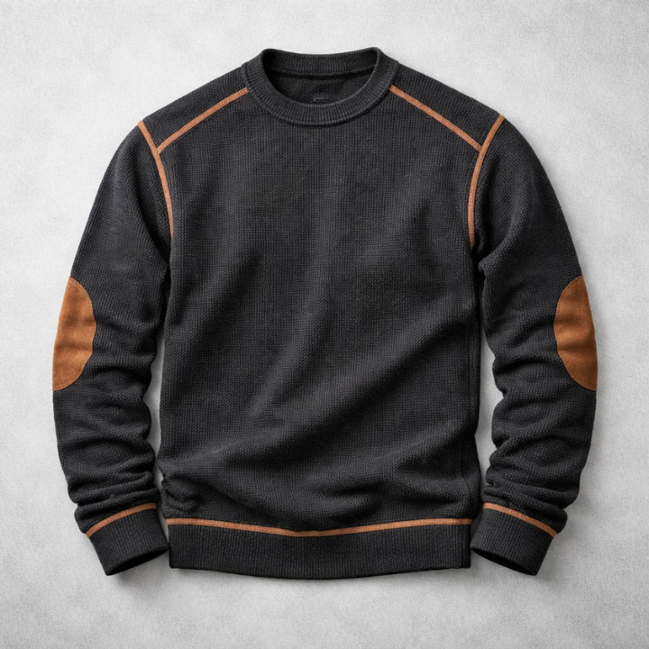 Schwarzer Herren-Strickpullover mit Waffelstruktur, Rundhalsausschnitt sowie braunen Ellbogen-Patches und Paspelierungen.