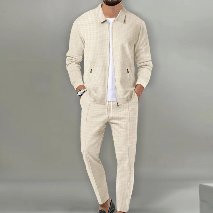 Beiger Herren-Zweiteiler in Waffeloptik mit Reißverschluss-Jacke, Hemdkragen und eleganter Hose für einen modernen Look.