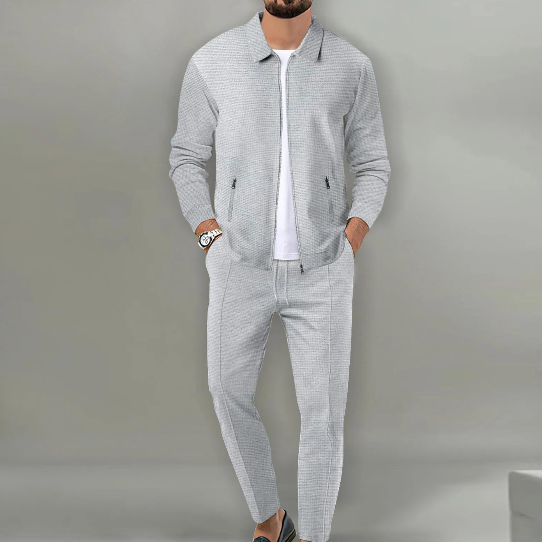 Grauer Herren-Zweiteiler in Waffeloptik mit Reißverschluss-Jacke, Hemdkragen und eleganter Hose für einen modernen Look.