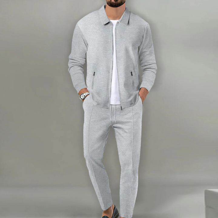 Grauer Herren-Zweiteiler in Waffeloptik mit Reißverschluss-Jacke, Hemdkragen und eleganter Hose für einen modernen Look.