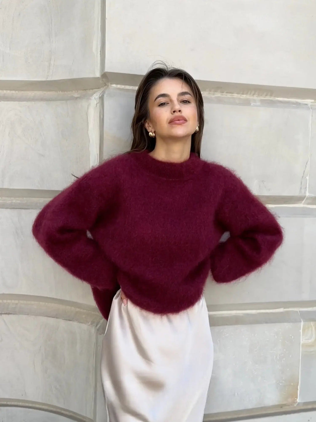 Flauschiger, weinroter Damen-Pullover mit Rundhals in lockerer Passform, kombiniert mit einem eleganten hellen Rock.