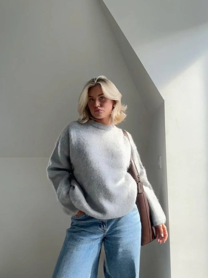 Flauschiger, hellgrauer Damen-Pullover mit Rundhalsausschnitt in lockerer Passform, kombiniert mit blauer Jeans.