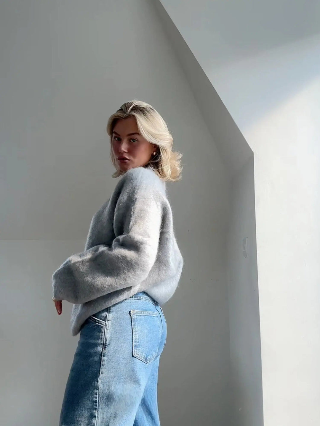Flauschiger, hellgrauer Damen-Pullover mit Rundhals in lockerer Passform, kombiniert mit lässiger Jeans für einen modernen Look.