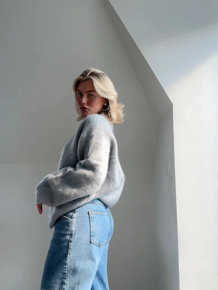 Flauschiger, hellgrauer Damen-Pullover mit Rundhals in lockerer Passform, kombiniert mit lässiger Jeans für einen modernen Look.