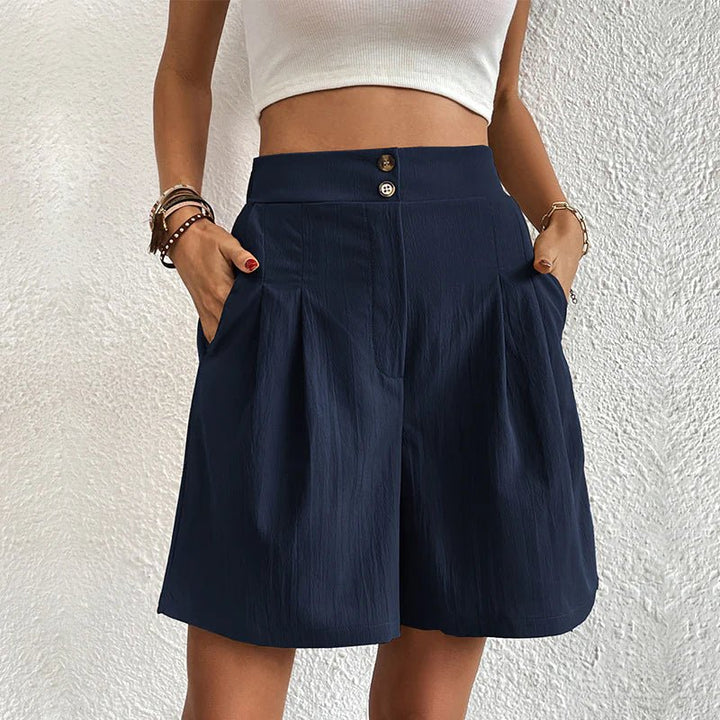 Dunkelblaue High Waist Shorts mit Bundfalten, weitem Beinschnitt und doppelter Knopfleiste am hohen Bund.